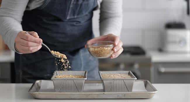 sprinkling walnuts and brown sugar onto raw banana bread