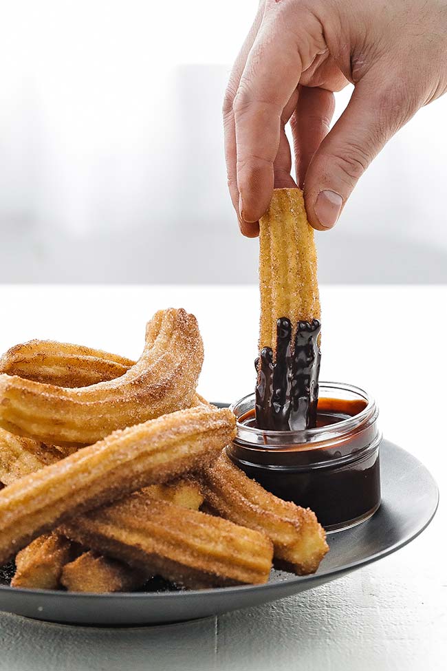dipping a churro in chocolate sauce