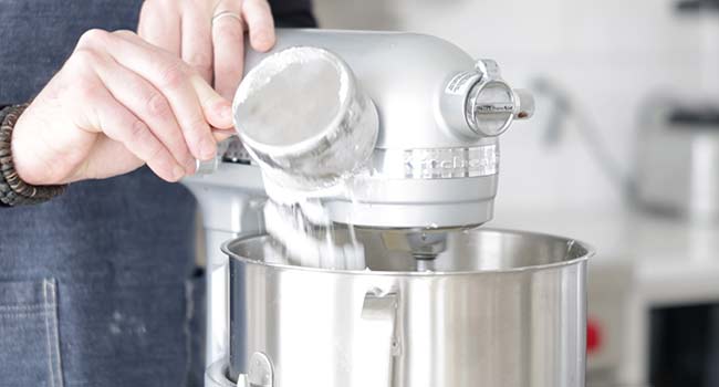 adding powdered sugar to a coconut cake