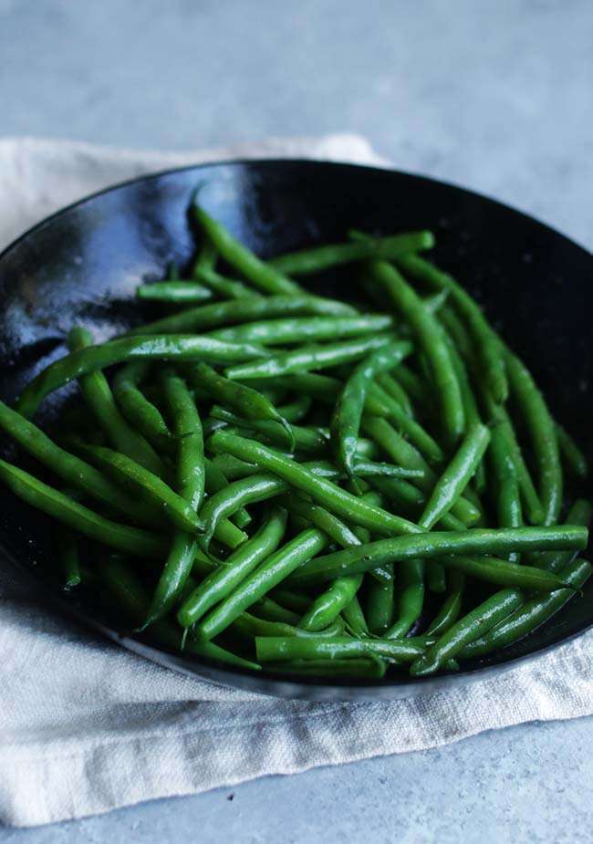 cooked butter glazed green beans in a frying pan