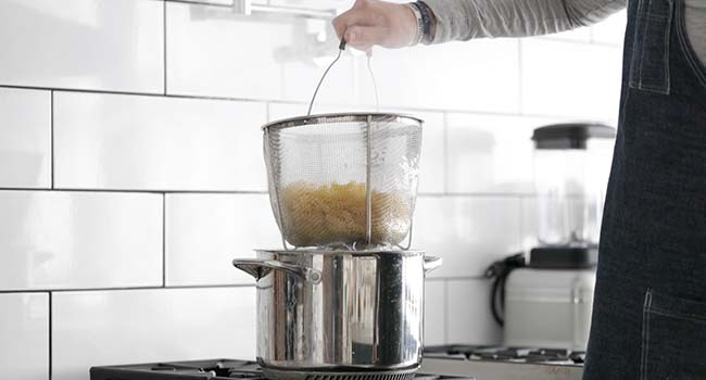 draining boiled noodle from a hot pot of water