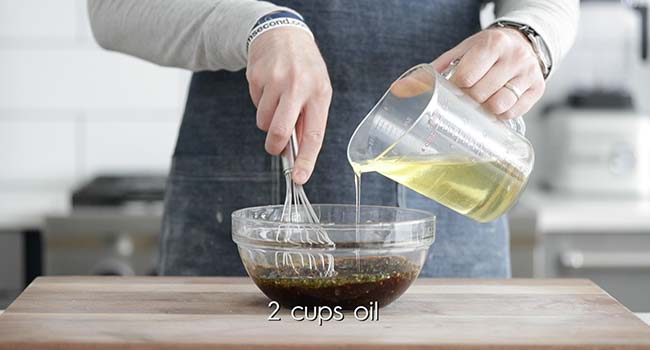 making a homemade balsamic vinaigrette by pouring oil into a bowl of vinegar