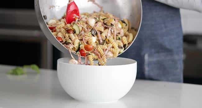 adding italian pasta salad to a large serving bowl
