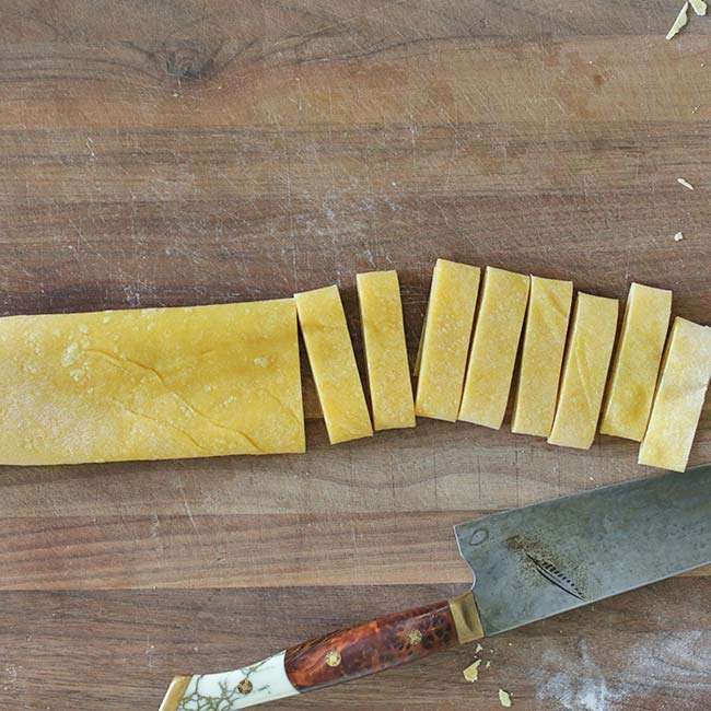 cutting homemade fresh pasta on a cutting board