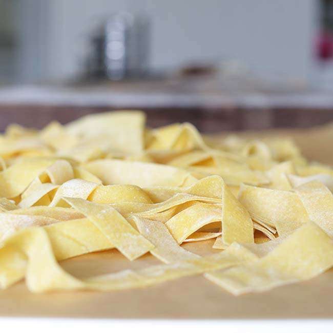 homemade pappardelle pasta with flour on parchment paper