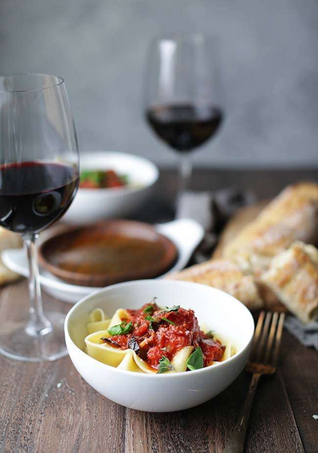 bowl of pasta with tomato sauce with bread and red wine