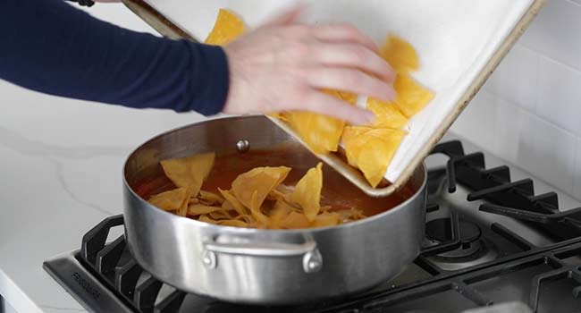 adding fried corn tortilla chips to the chilaquiles