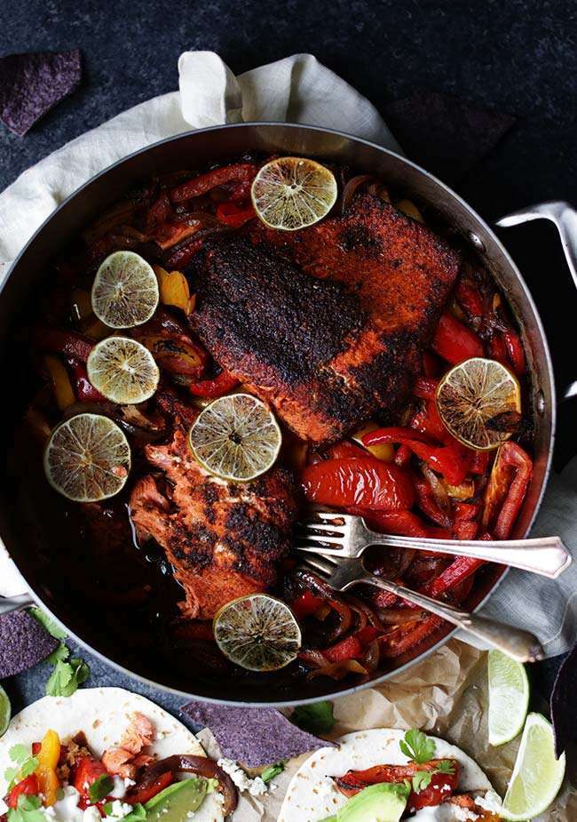 cook salmon and peppers in a pan with limes and forks