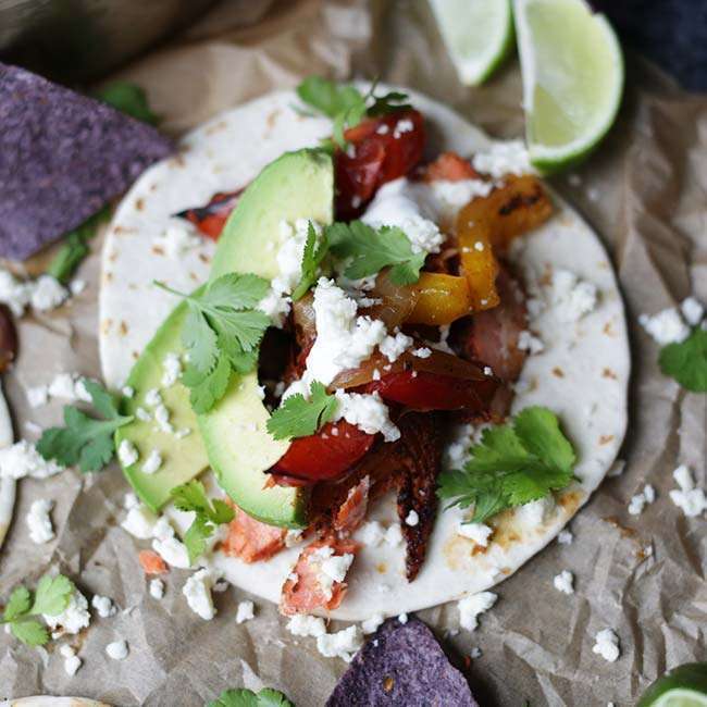 Spicy Baked Salmon Fajitas Recipe with Roasted Peppers and Onions on parchment paper