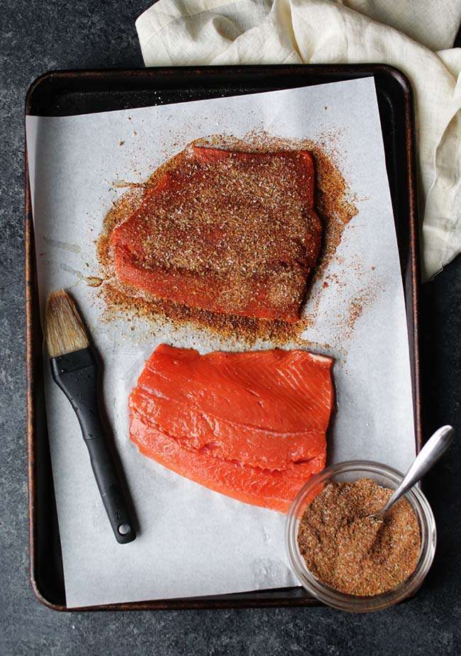 salmon fillets on a sheet tray with a brush of olive oil and spicy rub