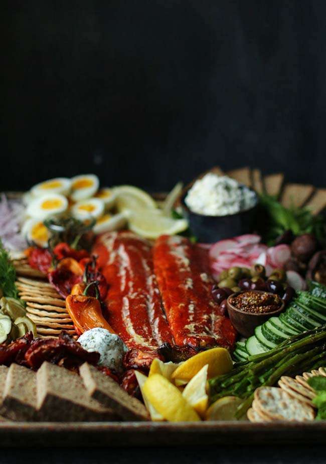 large platter with smoked fish, bread, lemons, vegetables and cheese