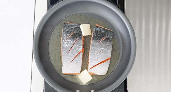 adding butter to pan seared salmon