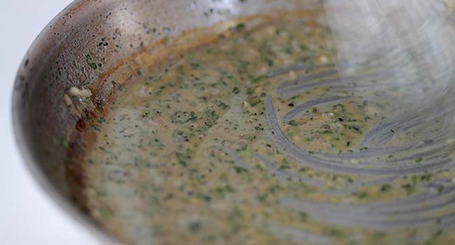 whisking a butter sauce together in a pan