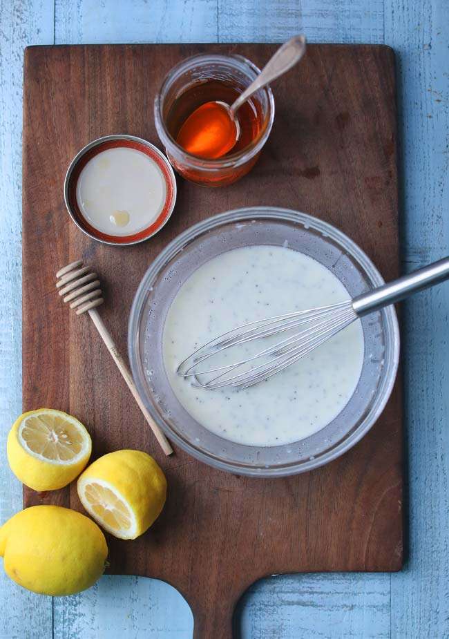 making a poppy seed dressing with lemon and honey in a bowl
