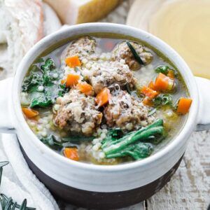 bowl of wedding soup with meatballs, carrots and escarole
