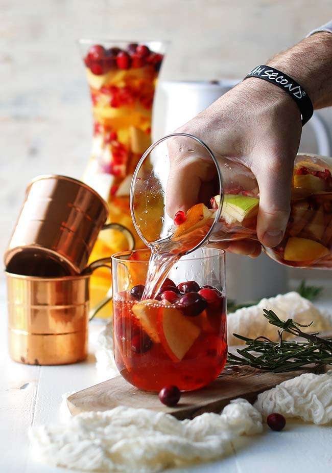 pouring a fall sangria into a serving glass