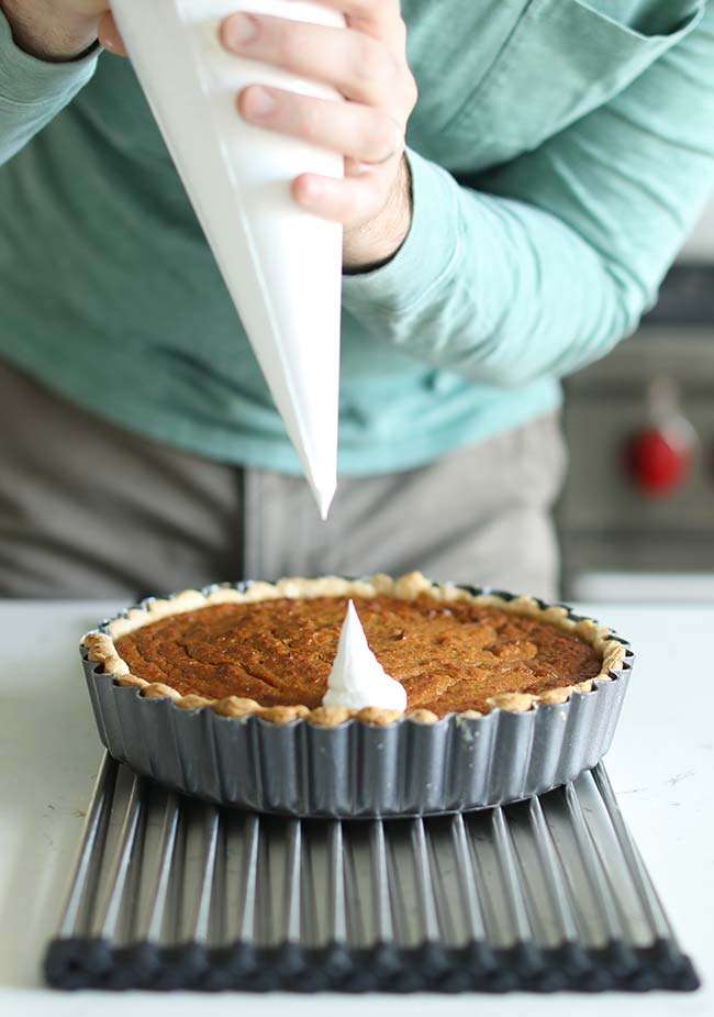 piping marshmallow merengue onto a baked sweet potato pie