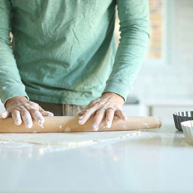 rolling out a pie crust dough on a counter top with a rolling pin