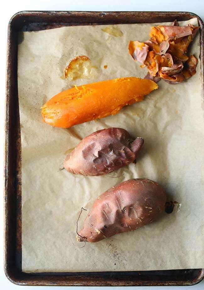 baked sweet potatoes on a sheet tray with parchment paper