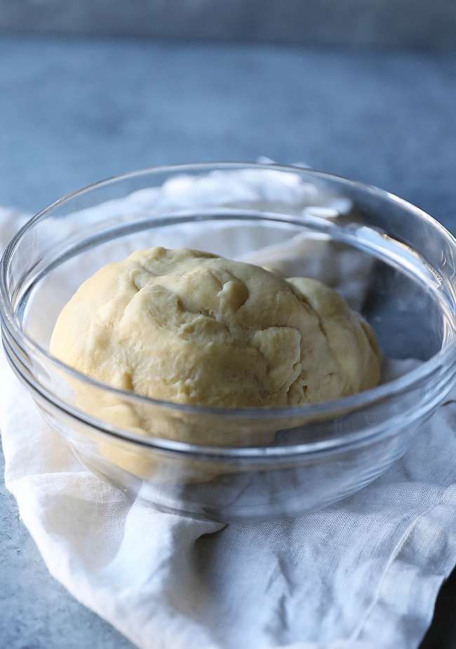 dough in a bowl resting under a towel