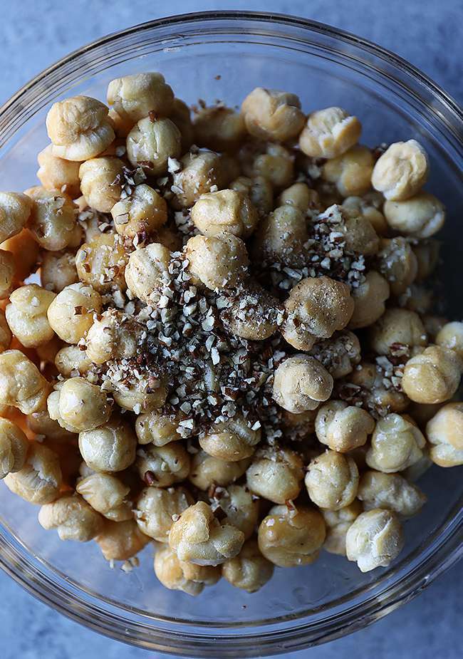 fried dough balls in a bowl being tossed with honey and pecans