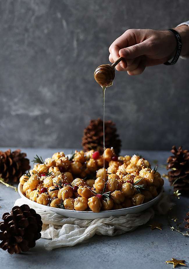 drizzling honey on a struffoli wreath on a plate