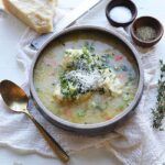 bowl of soup with dumplings, cheese and fresh herbs