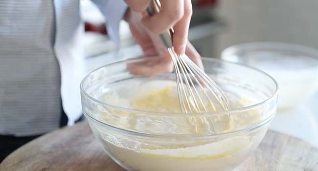 adding milk to a bowl of flour