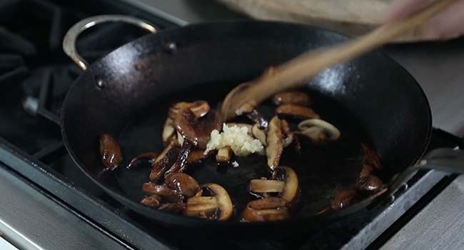 stirring garlic into a pan with mushrooms