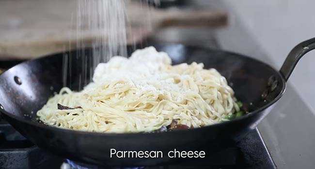 adding cheese to cooked pasta