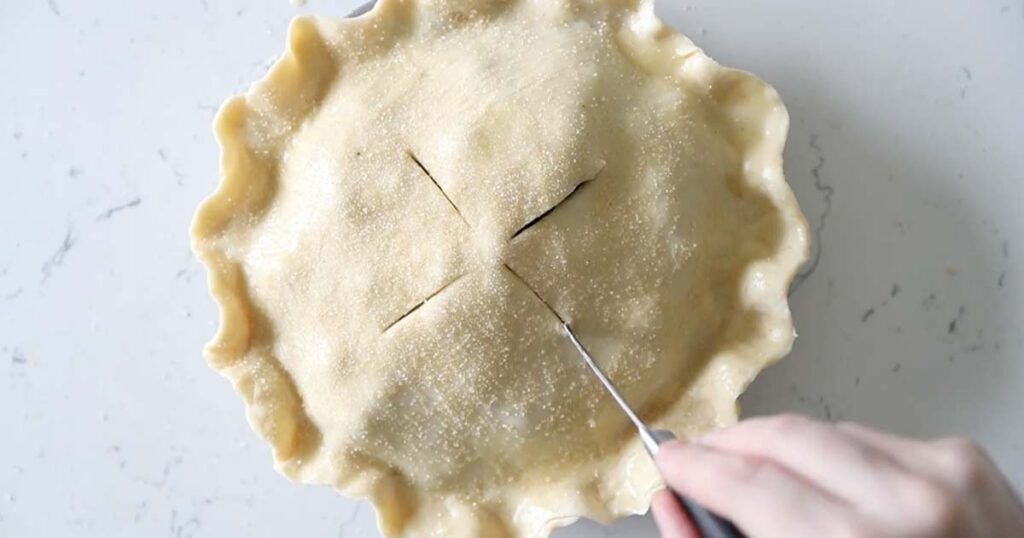 making slits in a blueberry pie