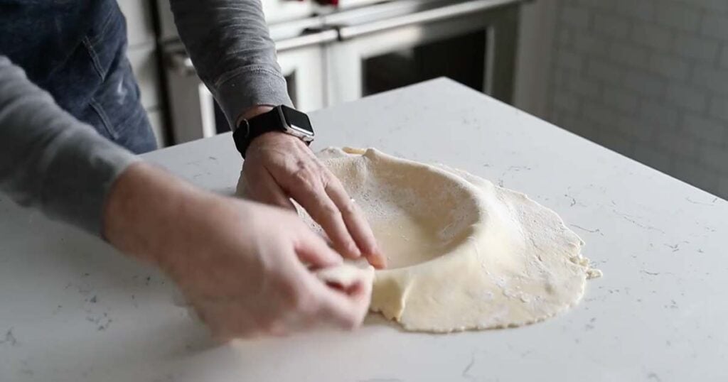 forming a pie dough to a pie tin