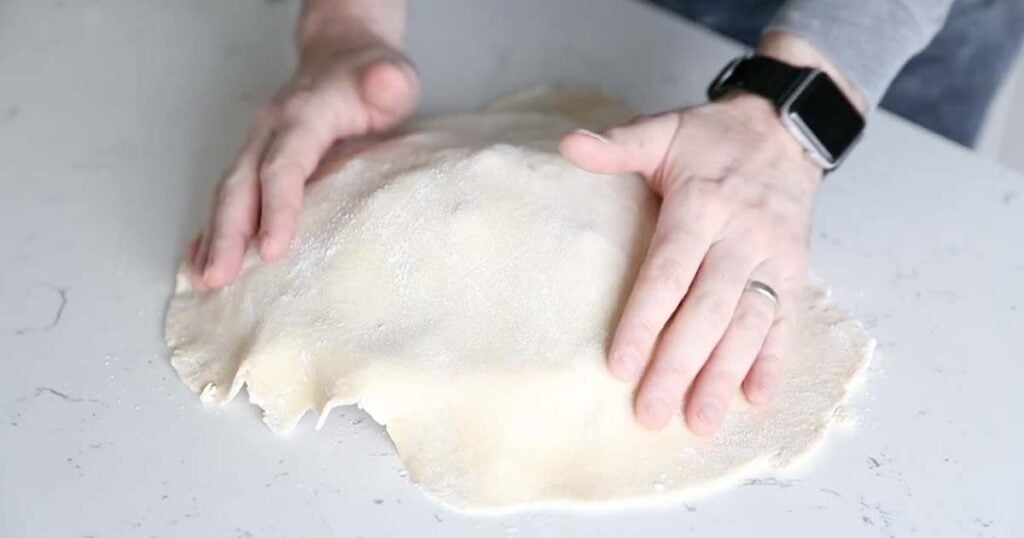 adding a pie dough over the top of a pie