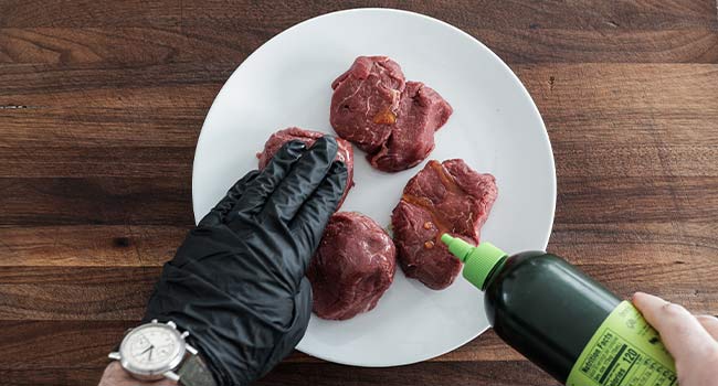 adding oil to steaks