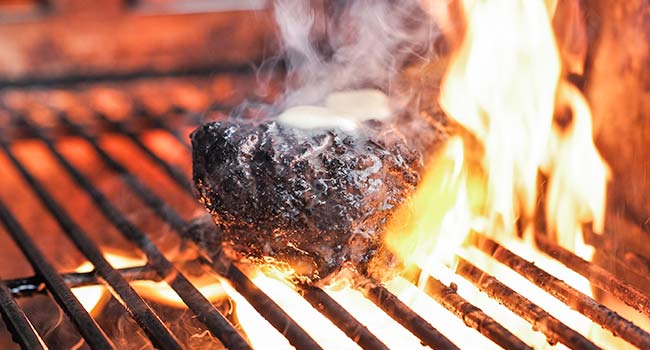 butter on steaks on a grill