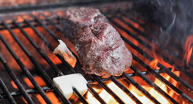 butter next to steaks on a grill