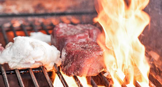 meat fat next to steaks on a grill