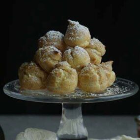 glass plate full of cream puffs with powdered sugar