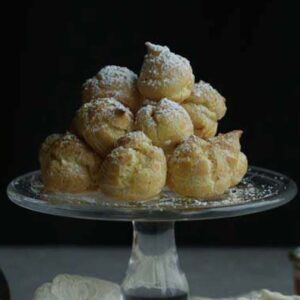 glass plate full of cream puffs with powdered sugar
