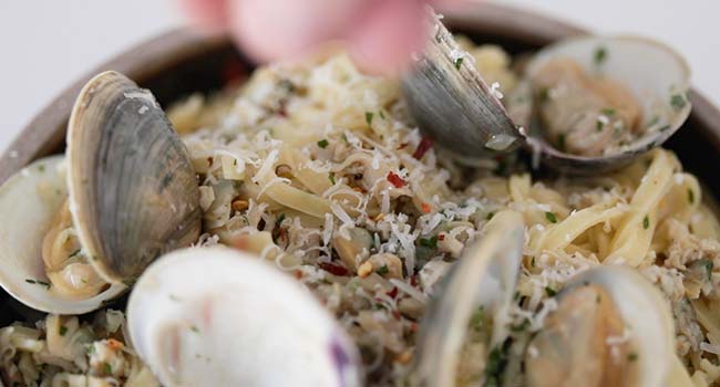 garnishing a linguine with clam sauce with parsley and herbs