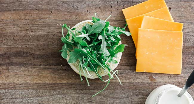 adding arugula to a bun