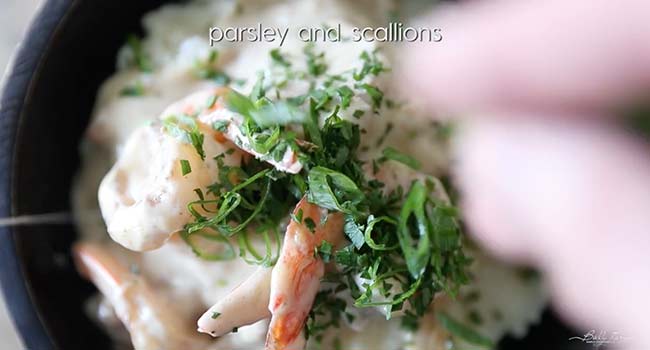 garnishing shrimp and grits with green onions