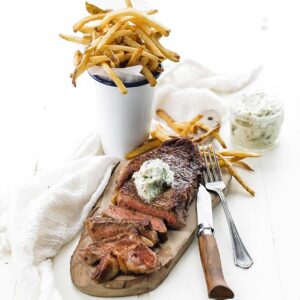 slice steak with butter and fries on a cutting board