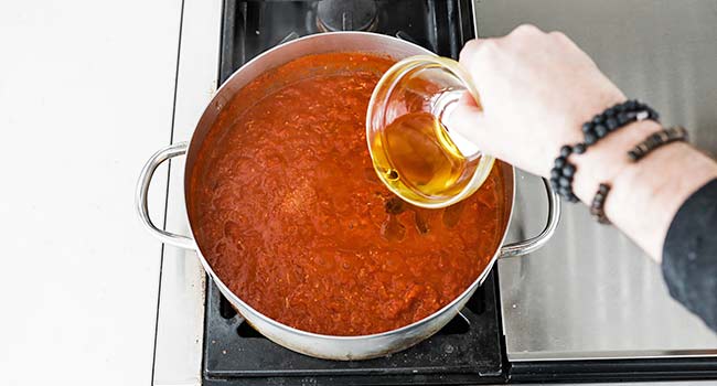 adding olive oil to a pot of arrabbiata sauce