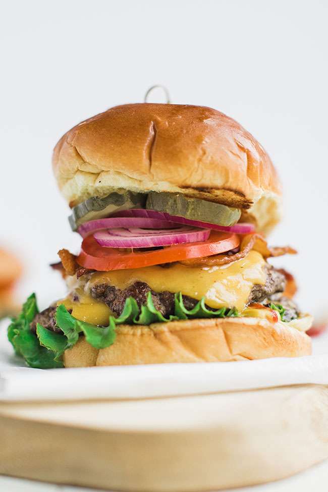 Big cheeseburger with American cheese on a brioche bun with lettuce, tomato and onion