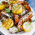 grilled lobster tails on a platter with lemons