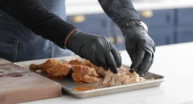 pulling slow cooked chicken on a sheet tray