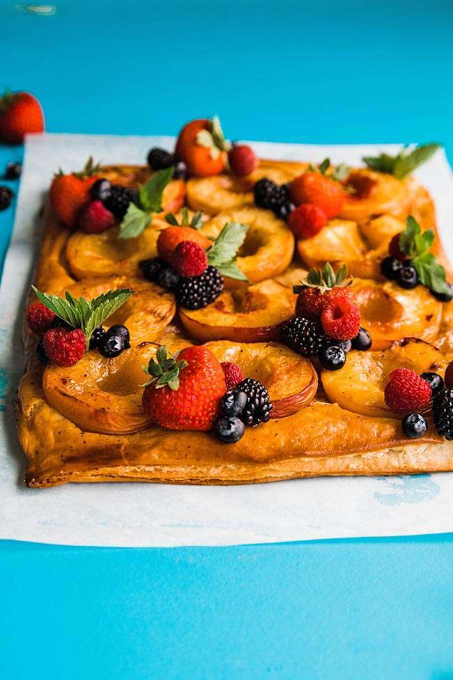 fresh peach tart on puff pastry with berries