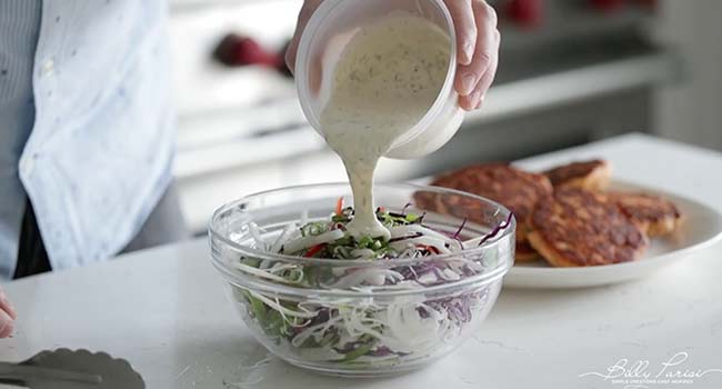 adding a creamy dressing to a bowl of vegetables