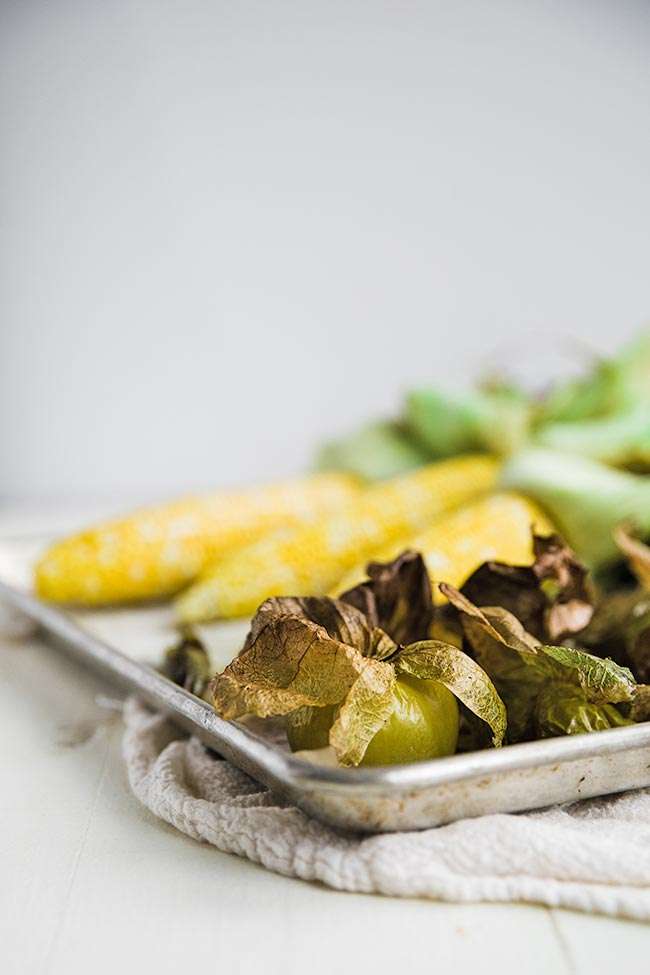 roasted tomatillos and corn on a sheet tray
